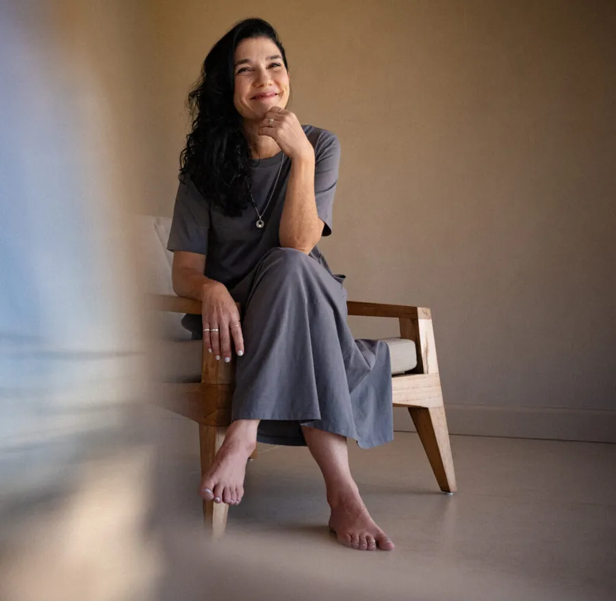 Andrea Carranza E., fundadora de ADENTRO, sentada en una silla de madera junto a una ventana