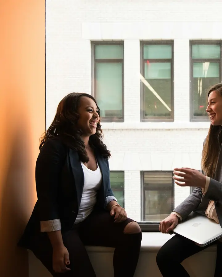 Dos mujeres conversando junto a una ventana